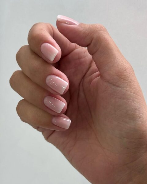 Zdjęcie dłoni ze zbliżeniem na średniej długości, kwadratowe paznokcie w kolorze nude pink. To paznokcie na zaręczyny.