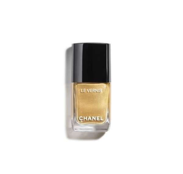 Złoty lakier do paznokci Chanel Le Vernis w eleganckiej szklanej buteleczce z czarną nakrętką i białym napisem, sfotografowany na białym tle.