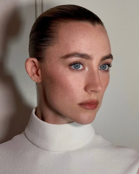 Zdjęcie aktorki Saoirse Ronan, w blond włosach, zaczesanych do tyłu. U niej widać, że błędy w makijażu, które postarzają, nie pojawiają się. Ma zaczesane brwi, delikatny makijaż ust. Ubrana jest w biały top ze stójką.