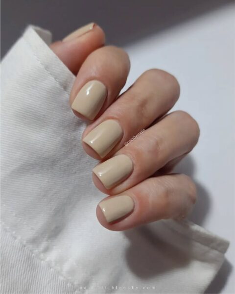 Zdjęcie ze zbliżeniem na średniej długości, kwadratowe paznokcie, które mają modny, ślubny manicure na maj 2025: są w kolorze nude.