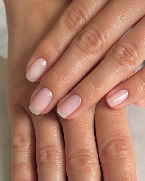 Zdjęcie dłoni ze zbliżeniem na długie, kwadratowe paznokcie w kolorze różowego nude. Dłonie układają się jedna na drugiej tak, by prezentować manicure.
