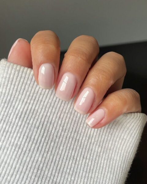 Zdjęcie dłoni ze średniej długości, kwadratowymi paznokciami w kolorze półtransparentnego beżu. To manicure z klasą, niekrzykliwy, elegancki.