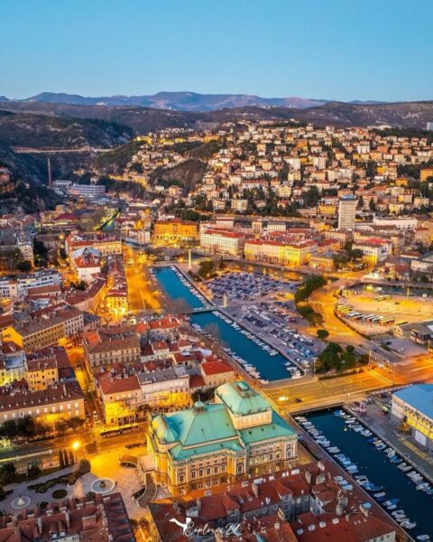 Zdjęcie, na którym widoczna jest Rijeka (Chorwacja). Widok z lotu ptaka, głownie na spacerową ulicę Korza. Wieczorowa pora. W tle widać wzgórza.