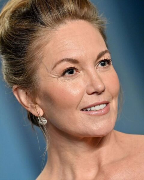 Zdjęcie aktorki Diane Lane ze zbliżeniem na jej twarz. Ma delikatny makijaż z różem twarzy i podkreślonymi oczami. Włosy spięte wysoko w kok. W uszach ma wiszące srebrne kolczyki z kryształkami.