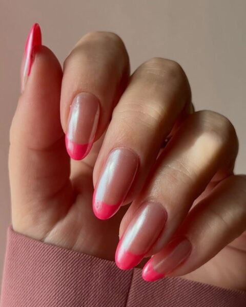 Zdjęcie dłoni ze zbliżeniem na długie, migdałowe paznokcie z różowy french manicure i chromowanym wykończeniem.