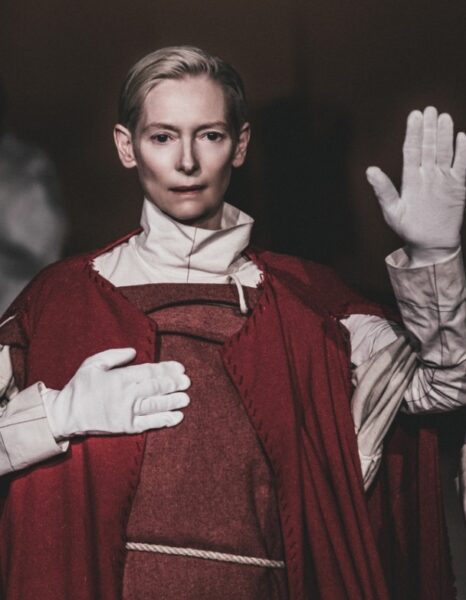Tilda Swinton w teatralnym, czerwono-beżowym kostiumie.