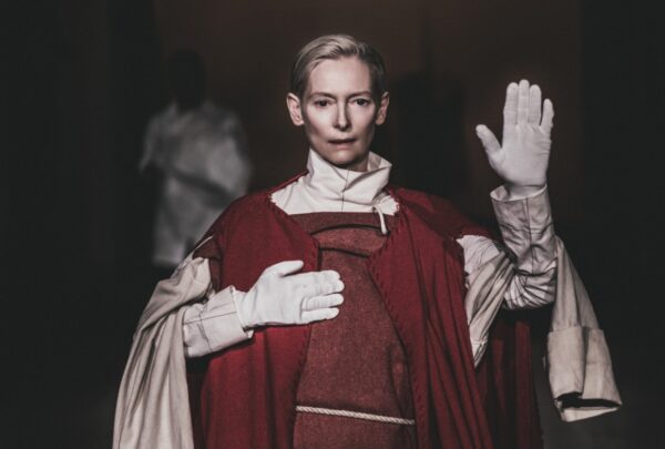 Tilda Swinton w czerwono-beżowym kostiumie teatralnym.