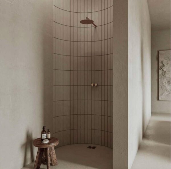 Przestronna łazienka w stylu fińskiego sisu z minimalistycznym prysznicem i drewnianym stołkiem – surowa elegancja i naturalne materiały.