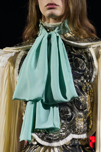 Zbliżenie na bogato zdobiony look Valentino Haute Couture z kontrastującą, miękko wiązaną kokardą w intensywnie pistacjowej zieleni – dramatyczny akcent w kolekcji lato 2025.