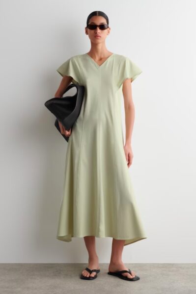 Modelka w minimalistycznej sukience midi w odcieniu pistacjowej zieleni, zestawionej z czarnymi dodatkami – letnia elegancja w nowoczesnym, monochromatycznym wydaniu.