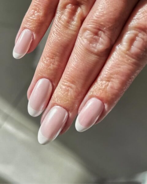Zdjęcie ze zbliżeniem na długie, owalne paznokcie z french manicure.