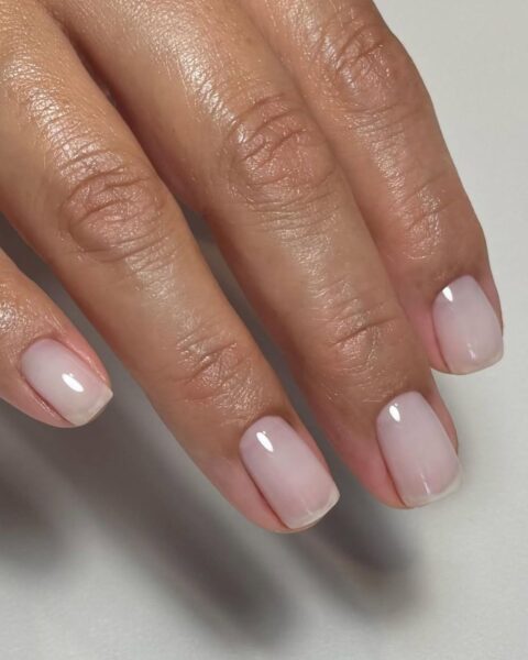 Zdjęcie dłoni ze zbliżeniem na old money manicure 2025, czyli krótkie paznokcie pomalowane odżywką.