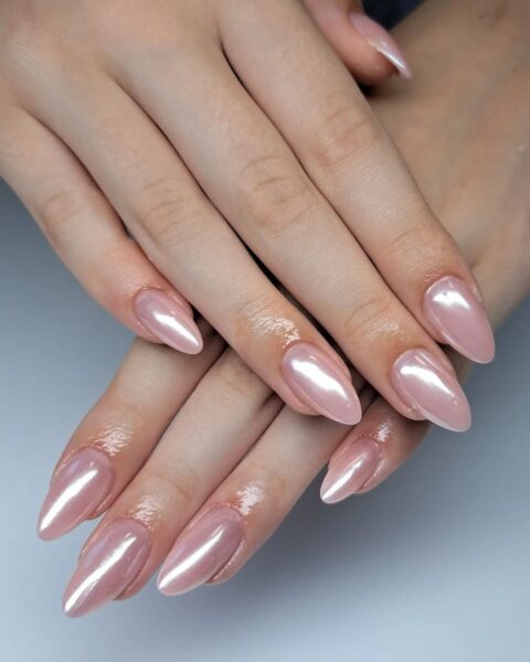 Zdjęcie dłoni z długimi, migdałowymi paznokciami w kolorze różowego nude z chromowanym wykończeniem. Dłonie pozują jedna na drugiej tak, by prezentować manicure.