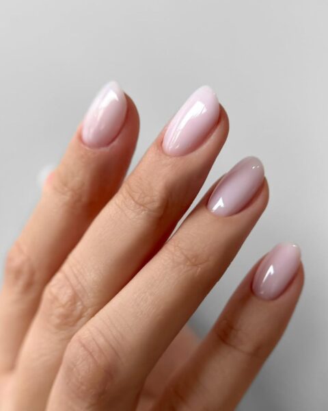 Zdjęcie dłoni z długimi, owalnymi paznokciami w kolorze pink nude. Dłoń pozuje w taki sposób, by prezentować swój manicure.