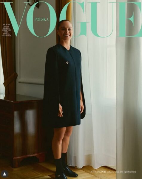 Kobieta w czarnej sukience i czarnych botkach pozuje we wnętrzu. Jest to okładka modowego magazynu.