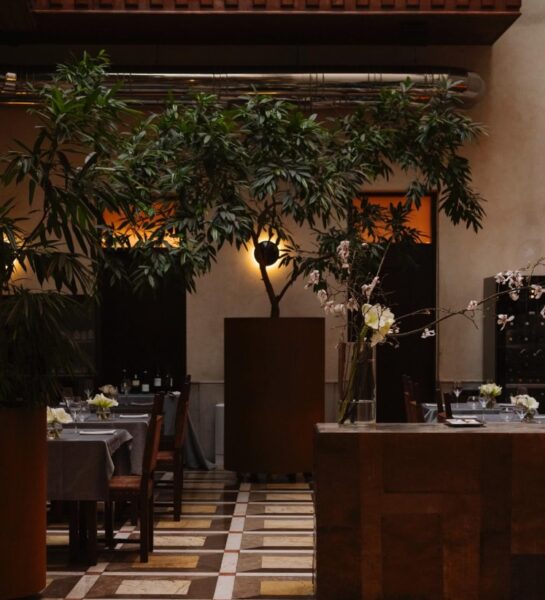 Wnętrze hotelu - w tle stoliki z krzesłami, bar. Ciemna tonacja zdjęcia.