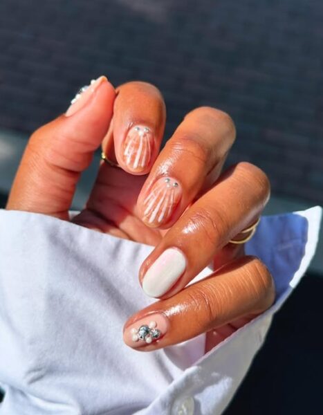 Jasny manicure z muszelkowymi zdobieniami.
