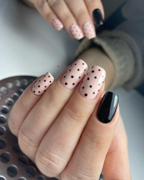 Manicure - jeden czarny paznokieć, reszta jasna w czarne kropki.