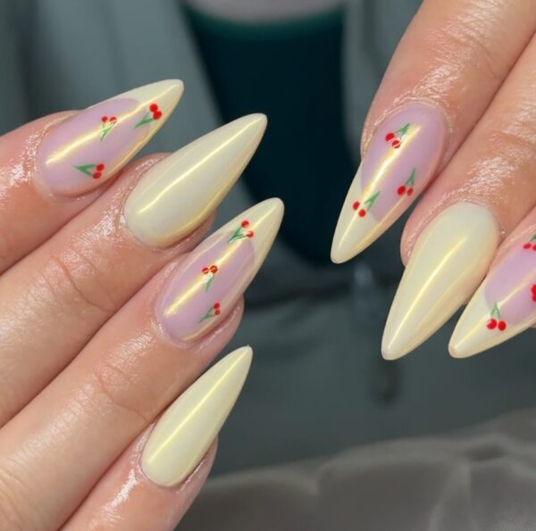 Manicure opalujący - kilka płytek pomalowanym na jasnożółty kolor, pozostałe na jasny. Na tych płytkach widać małe wisienki.