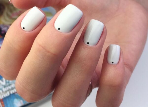 Kokosowy manicure z małymi, czarnymi kropkami na dole płytki.
