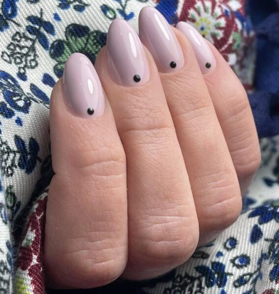 Jasny manicure z czarnymi kropkami.