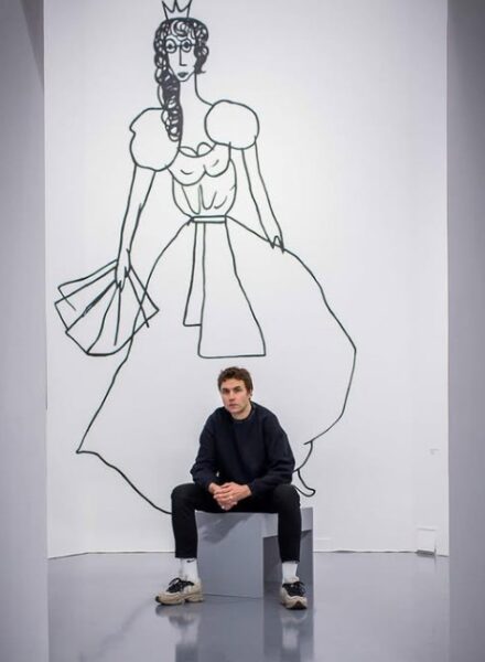 Artystka, Karol Radziszewski, siedzi w muzeum. Z tyłu rysunek kobiety.