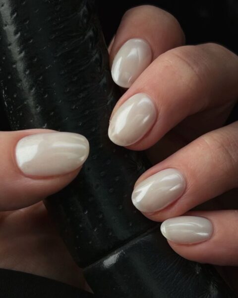 Zdjęcie dłoni ze zbliżeniem na chromatyczny manicure w kolorze białym. Paznokcie są krótkie i owalne. Dłoń zaciska się na kierownicy.