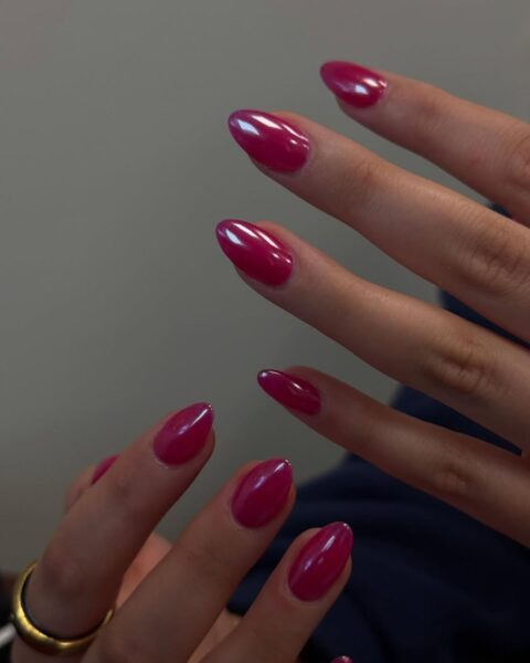 Zdjęcie dłoni ze zbliżeniem na malinowe paznokcie z chromowanym wykończeniem. Dłonie pozują tak, by prezentować manicure.