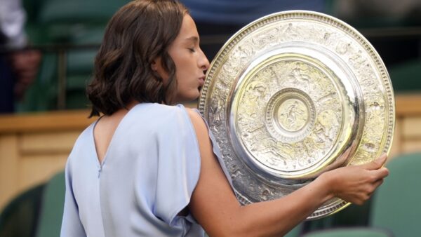 Kobieta w błękitnym ubraniu i z trofeum w ręce. Kobieta pozuje profilem.