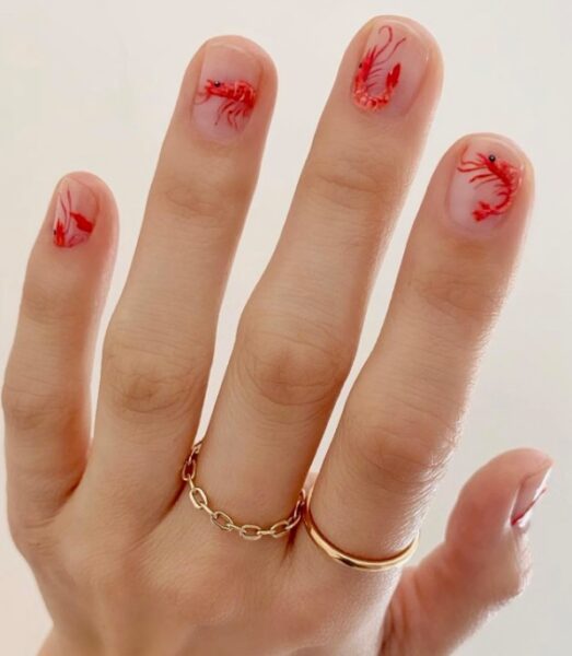 Jasny manicure z czerwonym zdobieniem - krabami.