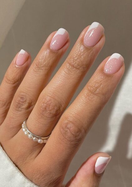 Jasny manicure z białym wzorkiem na końcu i z połyskiem.