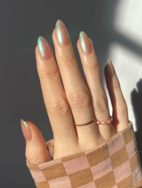 Jasny manicure z zielonym błyskiem.