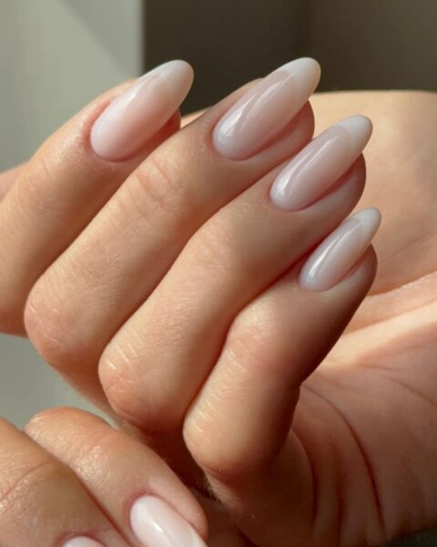 Zdjęcie dłoni ze zbliżeniem na french manicure, który będzie modny jesienią 2025. To foggy french manicure z efektem mgły. Dłonie układają się tak, by prezentować paznokcie.