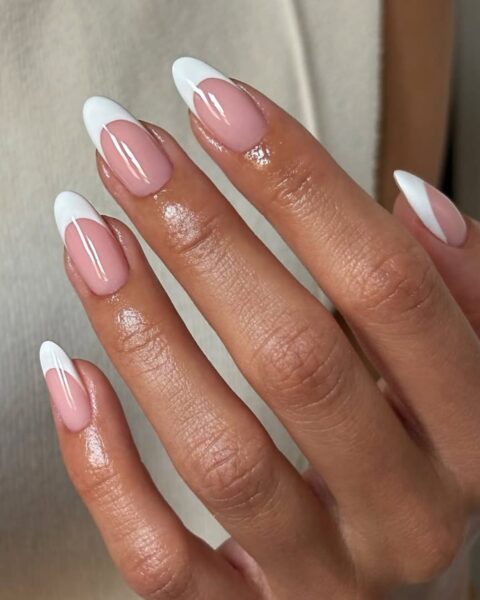 Zdjęcie dłoni z długimi, migdałowymi paznokciami z bold french manicure, czyli z grubą, białą końcówką.