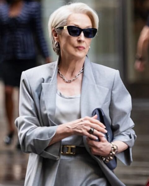 Zdjęcie Meryl Streep ubranej w szary komplet z marynarką, topem i spódnicą. Ma krótkie, siwe włosy, okulary przeciwsłoneczne na nosie, a pod ręką torebkę. To jej wizerunek z planu filmu "Diabeł ubiera się u Prady 2".