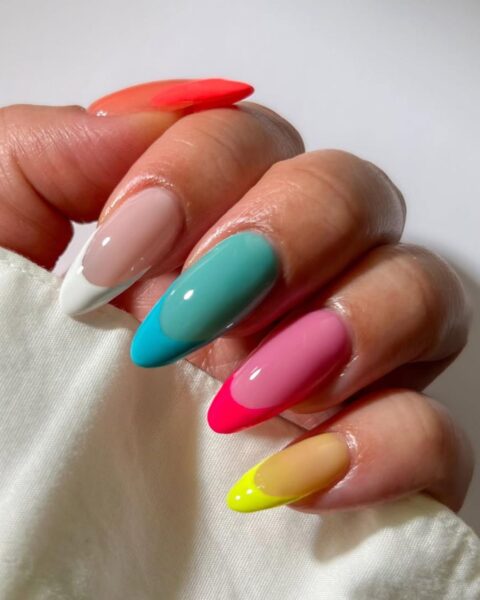 Zdjęcie dłoni z długimi, migdałowymi paznokciami z żelkowym french manicure. Każdy paznokieć ma inny kolor.