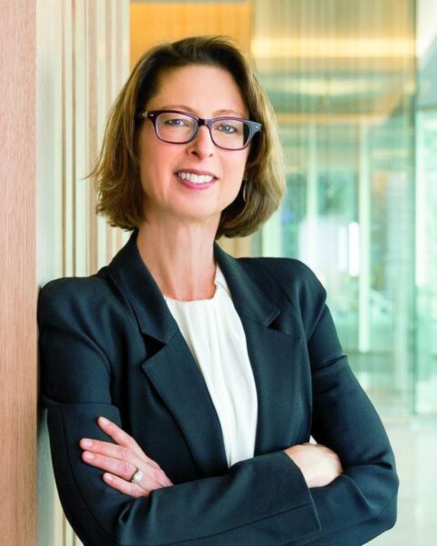 Na zdjęciu jest Abigail Johnson. To portret. Jest ubrana w marynarkę czarną oraz białą bluzkę. Ma krótkie włosy w kolorze ciemnego blondu. Na nosie okulary korekcyjne. Pozuje z założonymi rękami i widać jej naturalny manicure.