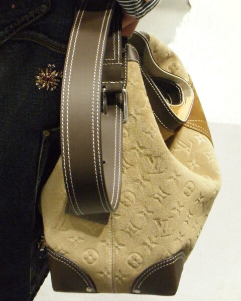 Zdjęcie torebki w kolorze brązowo-beżowym wykonanej z zamszowej skóry ozdobionej logo marki Louis Vuitton. Jest to zbliżenie z pokazu mody marki.