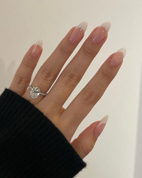 Zdjęcie dłoni ze zbliżeniem na paznokcie na ostatni weekend wakacji: french manicure z końcówkami w kolorze waniliowym. Na palcu serdecznym widać pierścionek z brylantem.