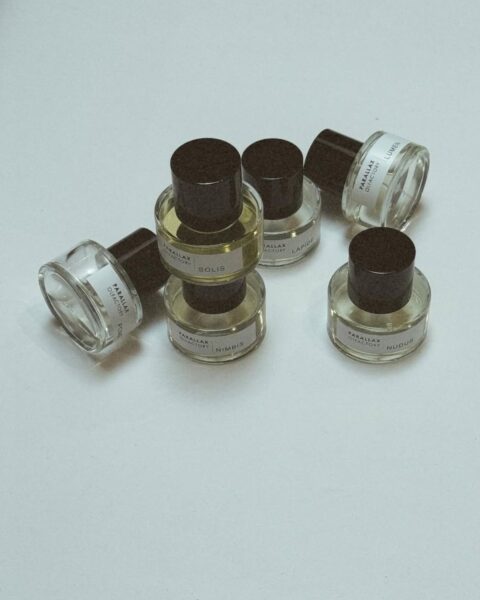 Zdjęcie przedstawiające kilka flakonów perfum wpisujących się w slow fragrance trend. Leżą w nieładzie na białym blacie.