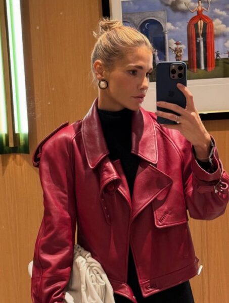 Kobieta w czarnym swetrze i czerwonej, skórzanej kurtce robi selfie.