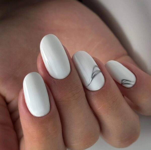 Biały manicure z metalicznym zdobieniem.