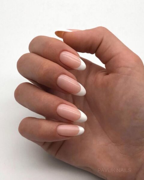 Zdjęcie dłoni ze zbliżeniem na długie, migdałowe paznokcie z deep french manicure.