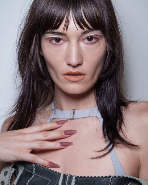 Modelka z bliska prezentująca drapieżny makijaż i paznokcie w kolorze brudnego różu, inspirowany trendami z wybiegów KNWLS. Manicure w najmodniejszych kolorach z wybiegów.