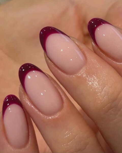 Wyjątkowo elegancki french manicure: burgundowe paznokcie w kształcie migdała, z głębokim, winnym odcieniem lakieru na końcówkach i klasyczną, mlecznoróżową bazą. Perfekcyjnie wykonane, błyszczące zdobienie w stylu deep french lub burgundy french, stanowiące szykowną alternatywę dla tradycyjnych czerwonych paznokci na jesień.
