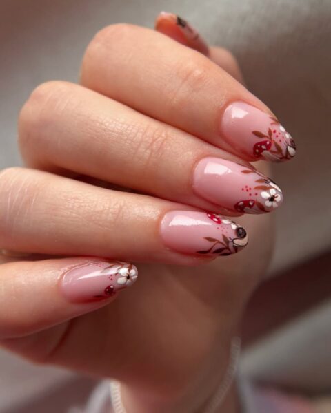 Uroczy, jesienny manicure na migdałowych paznokciach, idealny do inspirujących artykułów urodowych. Paznokcie mają bazę w kolorze mlecznego różu, a ich końcówki ozdobione są motywem leśnym. Wzór obejmuje czerwono-brązowe muchomorki, białe kwiatki, brązowe listki, a nawet maleńkie ślimaczki. To kreatywny french manicure z jesiennym akcentem, który łączy słodki design z elegancką formą.