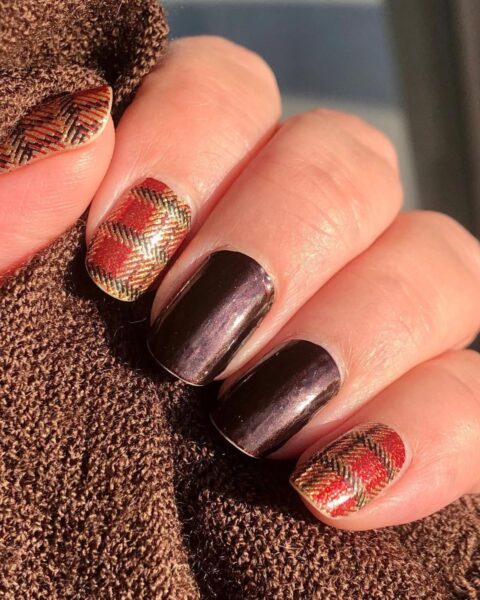 Pomysł na jesienny manicure. Krótkie paznokcie o kwadratowym kształcie, pomalowane połyskującym, metalicznym lakierem w kolorze gorzkiej czekolady. Palec serdeczny i mały zdobione złotym, błyszczącym wzorem w szkocką kratę. Inspirująca stylizacja paznokci, która idealnie pasuje do jesiennych swetrów i eleganckich, ciepłych stylizacji.