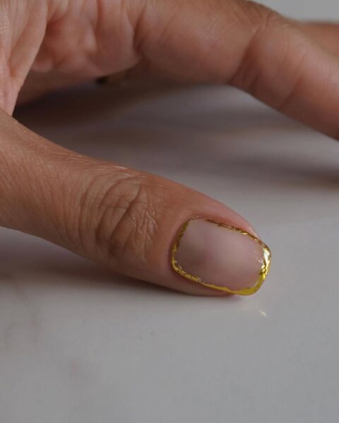 Minimalistyczny manicure na krótkiej płytce, w odcieniu klasycznego nude/mlecznego różu, z eleganckim, złotym akcentem. Mikro-french lub złota obwódka (gold foil) precyzyjnie obrysowująca krawędź paznokcia. Subtelna, luksusowa stylizacja idealna dla miłośniczek dyskretnej elegancji.