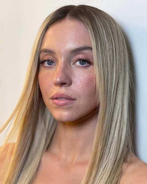 Opis alt do tego zdjęcia:Zbliżenie na twarz aktorki Sydney Sweeney z jasnym, świeżym makijażem "no make-up" i modnymi, sztucznymi piegami. Ma długie, proste, blond włosy z ciemniejszym odrostem. Makijaż i fryzura to idealna inspiracja dla naturalnego looku w duchu emocjonalnego SEO, podkreślającego klasę i autentyczność.